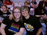Debbie and Denise prepare to enjoy the bout from rink-side seats. Denise is wearing an event t-shirt; the shirts were sold to benefit Kids Need to Read. © Denise Gary