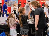 Nacole Vickory teaches Savannah and Peyton how to volunteer in the booth. © Robert Gary