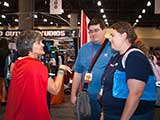 Just as Exhibitor Hall is closing, Denise received a special visit from a couple who she helped with a marriage proposal at the KNTR Geek Prom. © Bruce Matsunaga