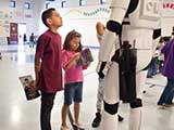 A child looks up in admiration at an awe-inspiring hero without realizing that behind his back, he holds in his hands the most powerful, transformative weapon he will ever come to know—a book. © Denise Gary