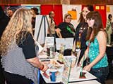 Whitney and Erin talk with a booth visitor. © Bruce Matsunaga