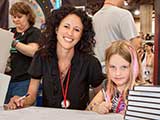 Marisa and Skylar Haarsma team up to sign calendars and sketches. © Bruce Matsunaga