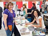 Marisa signs a KNTR 2012 calendar for Nacole Vickery. © Carl Wagner