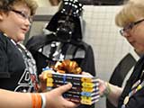 Debbie Brown presents Nicholas with a set of Actionopolis books for his birthday. Photo courtesy <em>Star Wars</em> Neighborhood