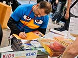 Steven signs a <em>Ty Cooney</em> book for a fan. © Robert Gary